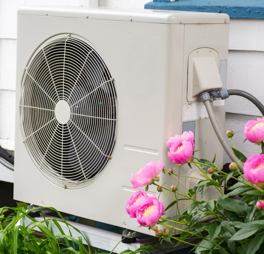 heat pump on the side of a house with some flowers